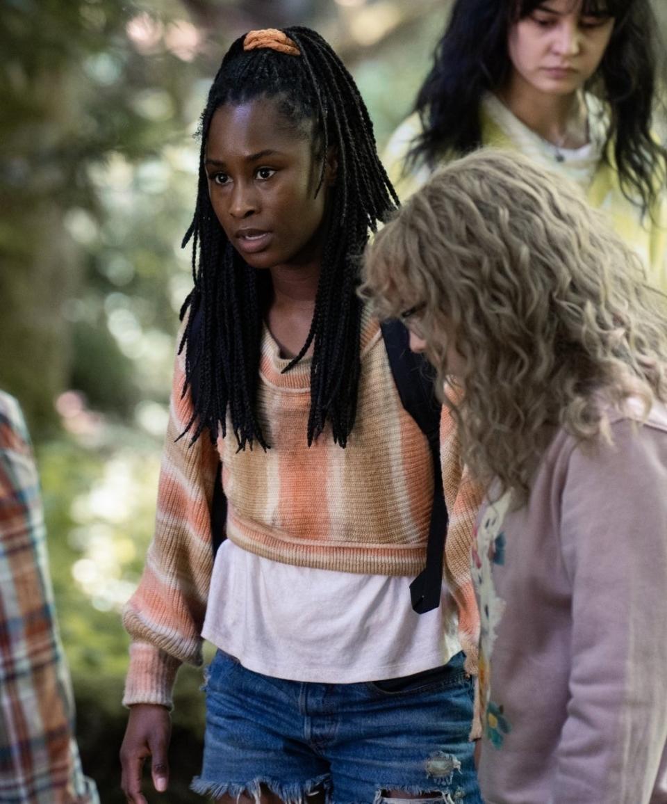 closeup of her in charcter in the woods with a group of women