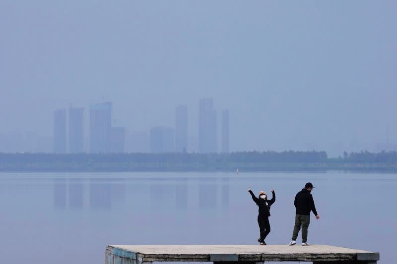 Woman wearing a face mask dances on the East Lake in Wuhan