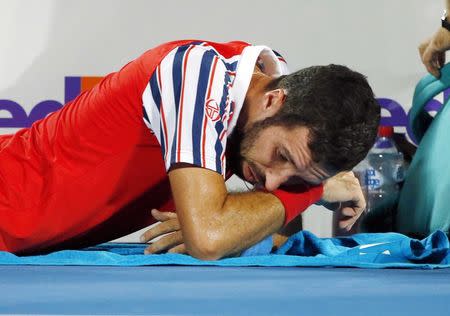 Mikhail Kukushkin of Kazakhstan lies on the court, after receiving treatment to his legs, during his men's singles final loss to Viktor Troicki of Serbia at the Sydney International tennis tournament in Sydney, January 17, 2015. REUTERS/Jason Reed