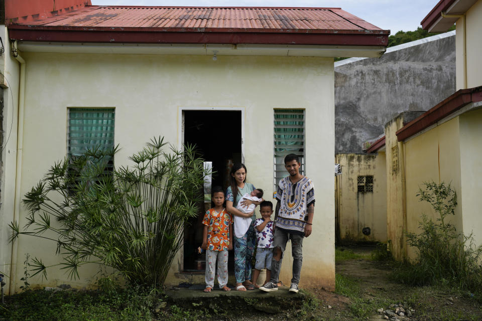 Jeremy Garing, right, his wife Hyancinth Charm Garing pose on Sunday, Oct. 23, 2022 with their children outside their home at a new community for victims of super Typhoon Haiyan in Tacloban, central Philippines on Sunday Oct. 23, 2022. Garing and his family settled at a relocation site three years ago after their village was wiped out when the super typhoon struck in 2013, killing six family members and his year-old daughter. (AP Photo/Aaron Favila)