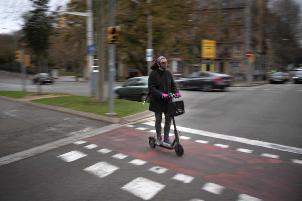 Victoria Martinez, 44, rides her electric scooter on her way home in Barcelona, Spain, Wednesday, Feb. 10, 2021. By May this year, barring any surprises, Martinez will complete a change of both gender and identity at a civil registry in Barcelona, finally closing a patience-wearing chapter that has been stretched during the pandemic. The process, in her own words, has also been “humiliating.” (AP Photo/Emilio Morenatti)