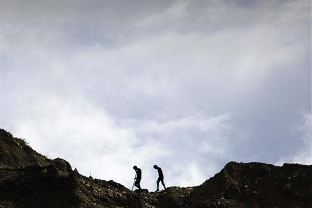 Hand-pickers walk as they search for jade through rubble dumped by mining companies at a jade mine in Hpakant township, Kachin State July 7, 2013. REUTERS/Minzayar