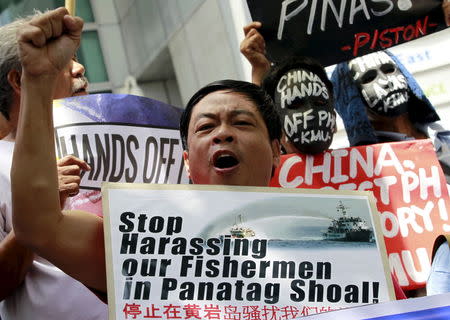 An activist raises his fist in protest against Beijing's incursions in the South China Sea outside the Chinese consulate in Makati City, metro Manila July 7, 2015. REUTERS/Romeo Ranoco - RTX1JBQR