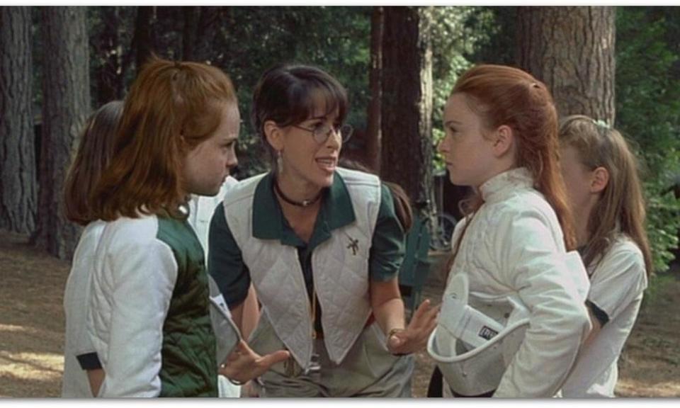 Camp counselor and children from "The Parent Trap" in a discussion amidst trees