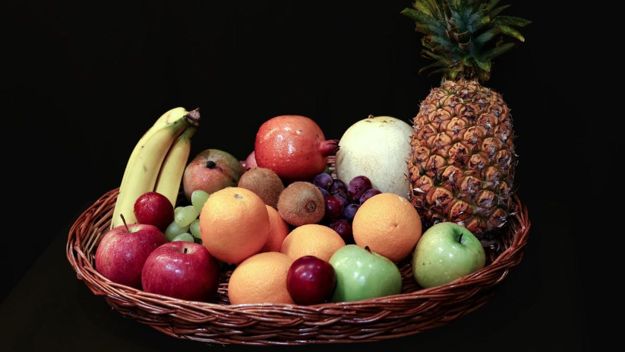 assorted colorful fruits in basket apple, banana, grapes, pineapple, oranges etc food photography macro close up