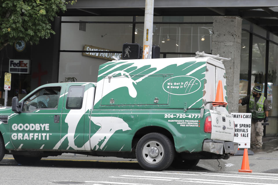 A worker with Goodbye Graffiti cleans a window, Wednesday, June 24, 2020, near the CHOP (Capitol Hill Occupied Protest) zone in Seattle. The area has been occupied since a police station was largely abandoned after clashes with protesters, but Seattle Mayor Jenny Durkan said Monday that the city would move to wind down the protest zone following several nearby shootings and other incidents that have distracted from changes sought by peaceful protesters opposing racial inequity and police brutality. (AP Photo/Ted S. Warren)