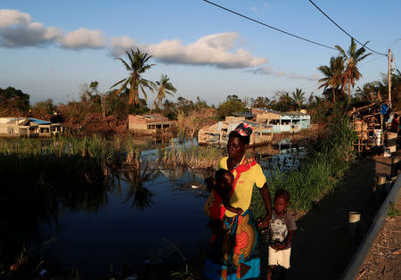 A woman walks with her children past flooded houses in the aftermath of Cyclone Idai in Tica near Beira, Mozambique March 31, 2019. REUTERS/Zohra Bensemra?