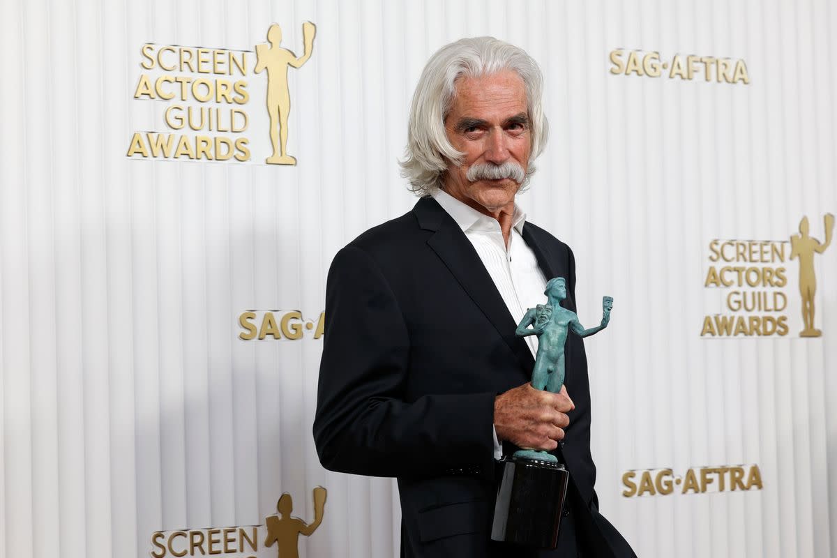 A white man with white hair and mustache wearing a black suit holds an award. . Frazer Harrison/Getty Images