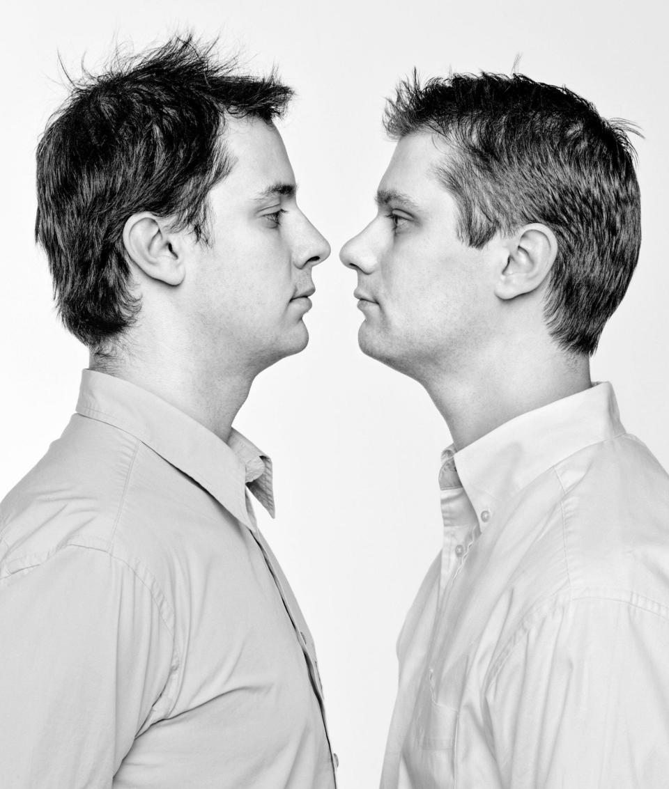 two look alike men face each other nose to nose with long sleeved shirts on