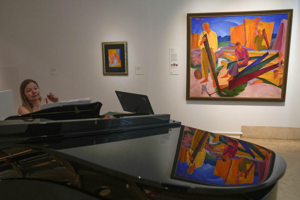 A pianist plays in front of a painting by Ukrainian artist Oleksandr Bohomazov called 'Sharpening of the Saws', seen on right, during the inauguration of the Ukraine art exposition at the Thyssen-Bornemisza museum in Madrid, Spain, Monday, Nov. 28, 2022. Against a backdrop of Russian attacks, border closures and a nail-biting journey across Europe, Madrid's Thyssen-Bornemisza National Museum has teamed up with Kyiv's National Art Museum of Ukraine to secretly bring dozens of Ukrainian 20th century avant garde artworks by road to the Spanish capital for a unique exhibition and statement of support for the war-torn country. (AP Photo/Paul White)