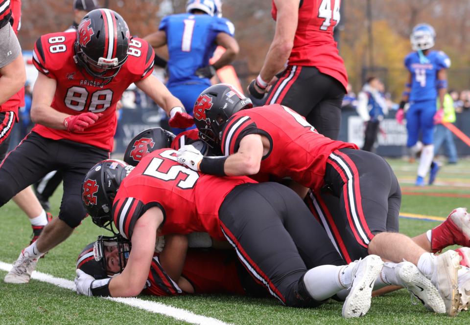 The North Quincy High football team piles on running back Nate Caldwell after a touchdown during the 89th Thanksgiving game against Quincy at Veteran's Memorial Stadium in Quincy on Thursday, Nov. 25, 2021.