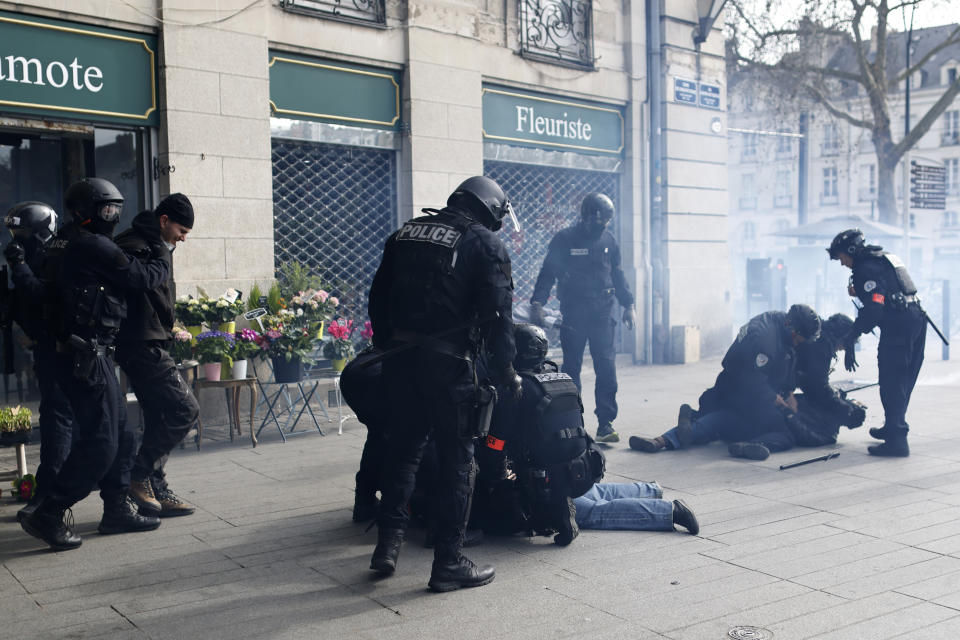 Police officers detain youths during a demonstration Tuesday, March 7, 2023 in Nantes, western France. Garbage collectors, utility workers and train drivers are among people walking off the job across France to show their anger at a bill raising the retirement age to 64, which unions see as a broader threat to the French social model. (Jeremias Gonzalez)