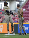 San Diego Padres' Fernando Tatis Jr. is greeted by first base coach David Macias after he singled against the Cincinnati Reds for his 500th career hit, during the top of the first inning of a baseball game Tuesday, May 21, 2024, in Cincinnati. (AP Photo/Carolyn Kaster)