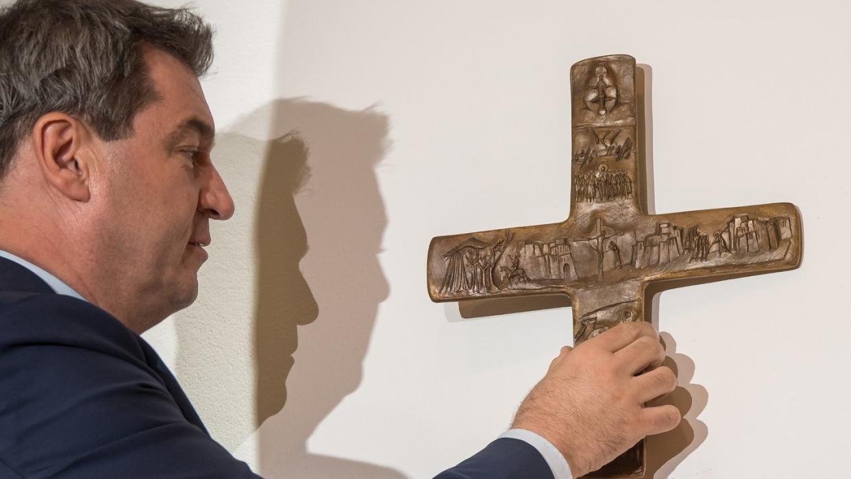 Bayerns Ministerpräsident Markus Söder hängt ein Kreuz im Eingangsbereich der bayerischen Staatskanzlei auf. Foto: Peter Kneffel