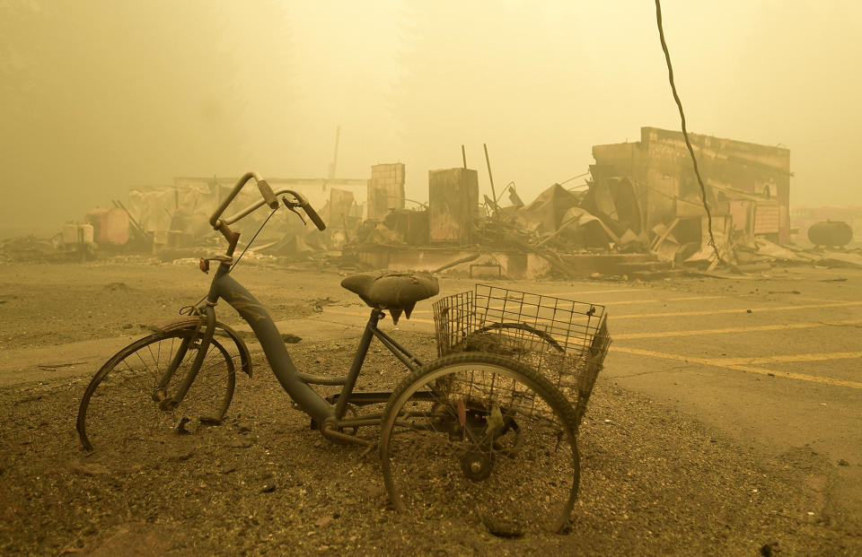 FILE - In this Sept. 11, 2020 file photo a trike stands near the burnt remains of a building destroyed by a wildfire near the Lake Detroit Market in Detroit, Ore. The blaze was one of multiple fires that burned across the state last month. Three Pacific Northwest law firms have filed a class action lawsuit against Pacific Power and its parent company, Portland-based PacifiCorp, alleging that the power company failed to shut down its power lines despite a historic wind event and extremely dangerous wildfire conditions. (Mark Ylen/Albany Democrat-Herald via AP, File)