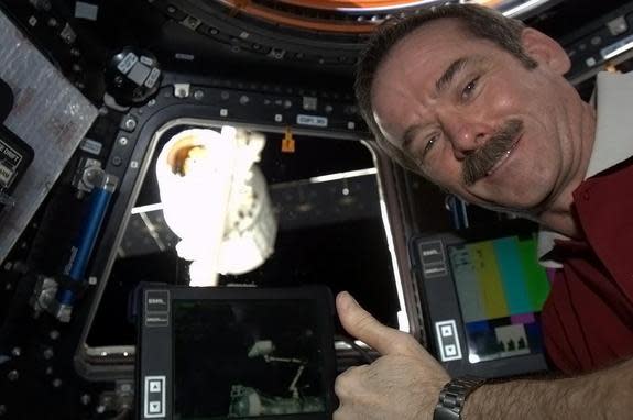 Canadian astronaut Chris Hadfield poses with SpaceX's Dragon capsule after it docked successfully with the space station.