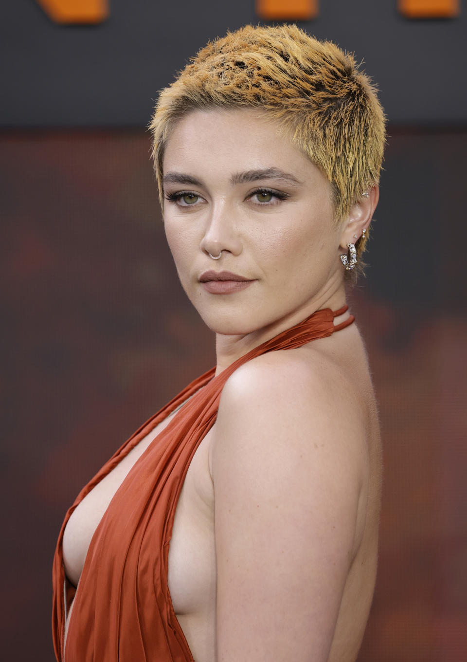 Florence Pugh arrives at the "Oppenheimer" UK premiere on July 13, 2023 donning a slick camo pixel orange-colored buzzcut