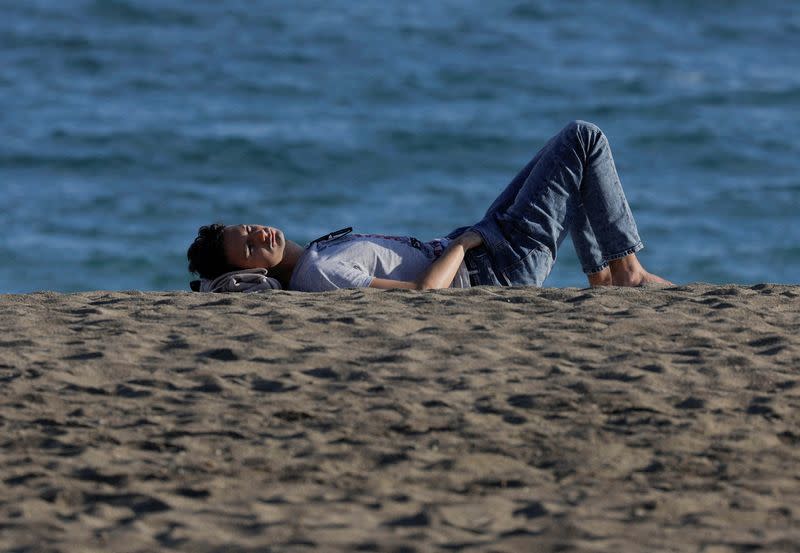 FILE PHOTO: A man enjoys the sun in front of the sea during unseasonably warm temperatures in Malaga