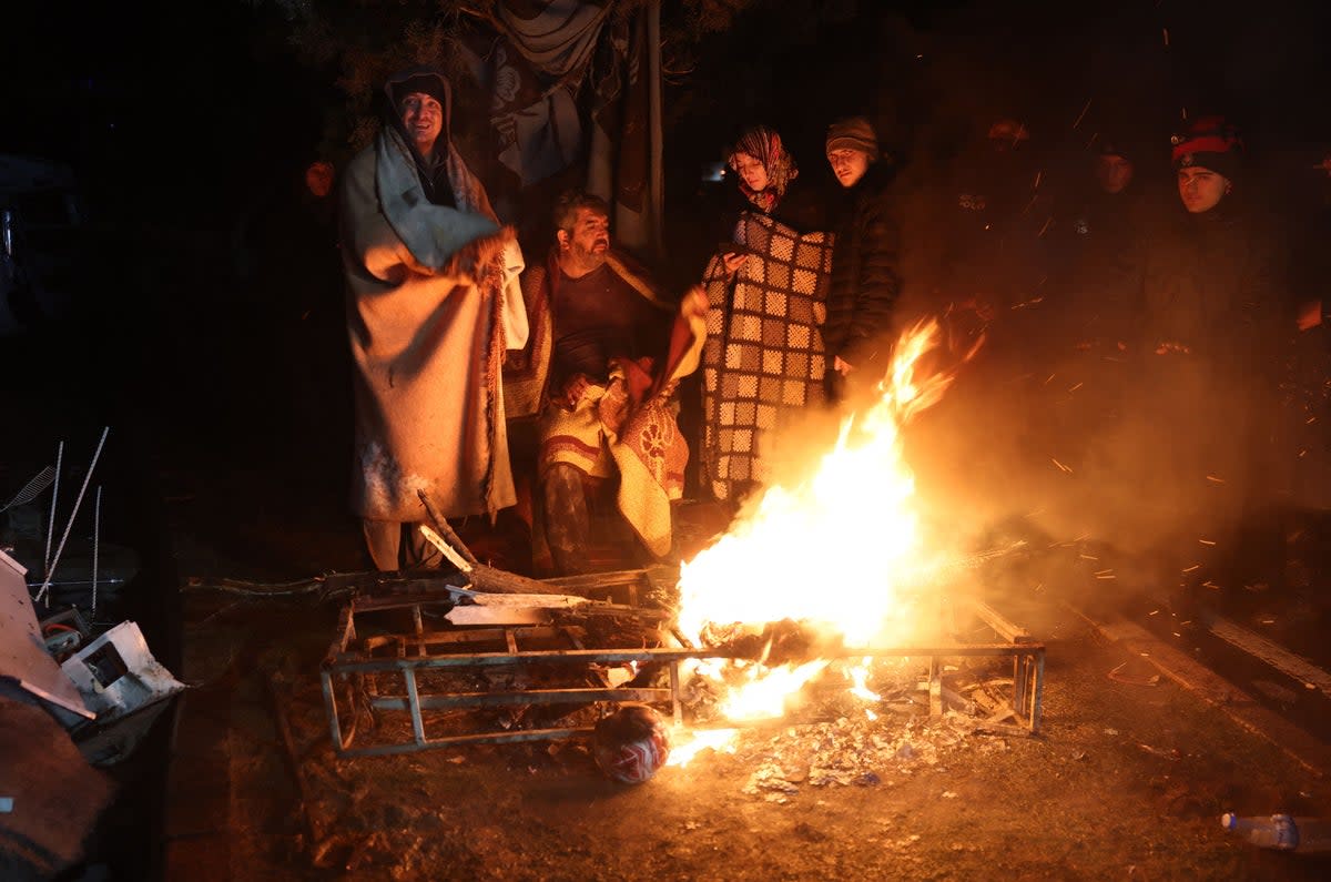 People warm themselves around a bonfire in the rubble in Kahramanmaras, Turkey, after a 7.8-magnitude earthquake struck the country’s southeast (AFP via Getty Images)