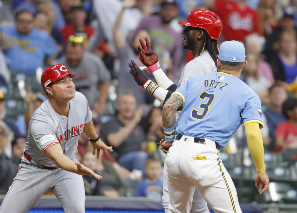 Cincinnati Reds' Elly De La Cruz, back right,reacts with third base coach J.R. House, left, after hitting a triple in the fifth inning of a baseball game against the Milwaukee Brewers, Friday, June 14, 2024, in Milwaukee. (AP Photo/Jeffrey Phelps)