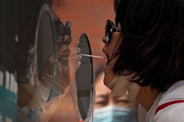 PHOTO: A woman gets her routine COVID-19 throat swab at a coronavirus testing site in Beijing, Aug. 23, 2022. (Andy Wong/AP)