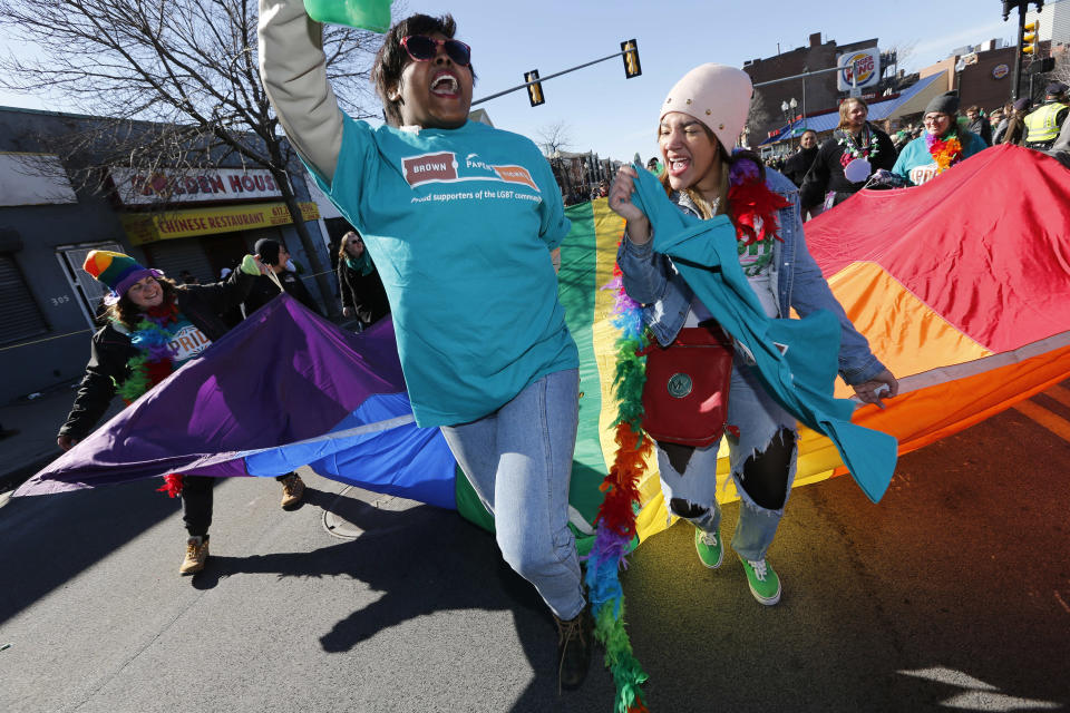 Alyssa Bowdre, center left, and Kia Dumas, center right, march with a rainbow flag in an alternative parade that follows behind the traditional St. Patrick's Day parade in the South Boston neighborhood of Boston, Sunday, March 16, 2014. (AP Photo/Michael Dwyer)