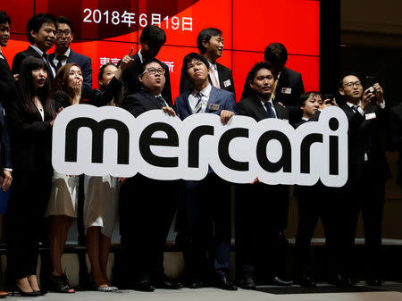 Mercari Inc. employees react as they hold the company's sign ahead of a ceremony to mark the company's debut on the Tokyo Stock Exchange in Tokyo, Japan, June 19, 2018. REUTERS/Kim Kyung-Hoon