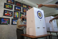 An Armenian man reads his ballot papers at a polling station during a parliamentary election in Yerevan, Armenia, Sunday, June 20, 2021. Armenians are voting in a national election after months of tensions over last year's defeat in fighting against Azerbaijan over the separatist region of Nagorno-Karabakh. (AP Photo/Sergei Grits)