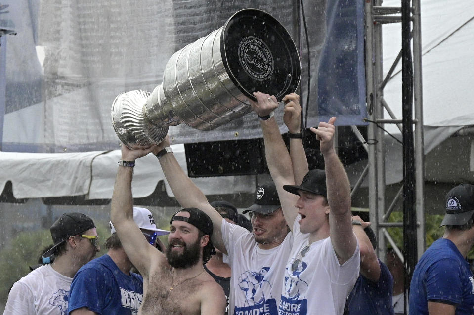 Tampa Bay Lightning right wing Nikita Kucherov, left, defenseman Mikhail Sergachev, center, and goaltender Andrei Vasilevskiy hoist the Stanley Cup during the NHL hockey Stanley Cup champions' championship celebration after their boat parade, Monday, July 12, 2021, in Tampa, Fla. (AP Photo/Phelan M. Ebenhack)