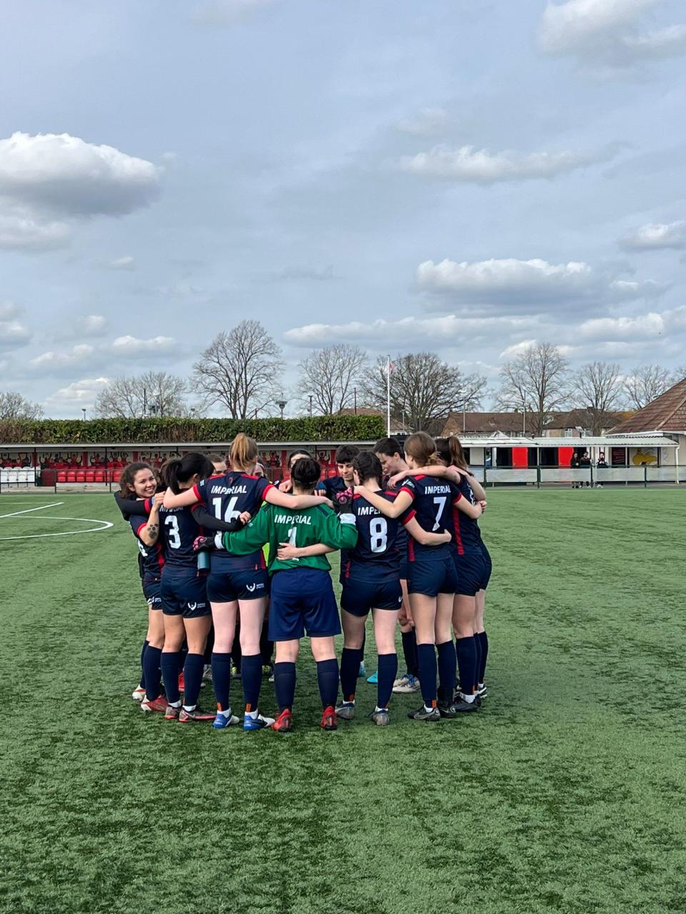 Members of the football club grouped together in a huddle 