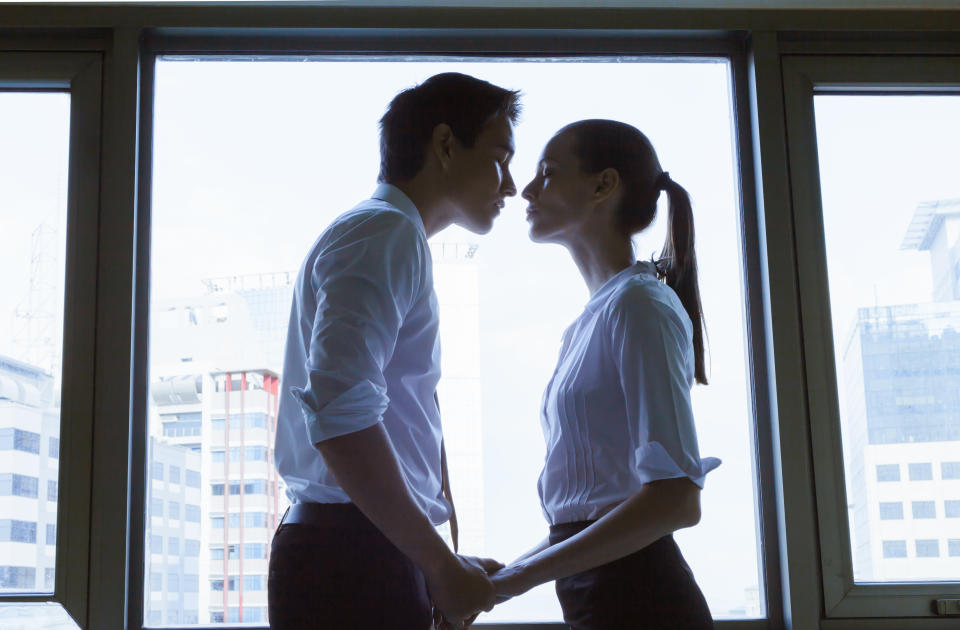 Two people in corporate wear about to kiss, affair at work