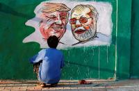 A man applies finishing touches to paintings of U.S. President Trump and India's PM Modi along a route that Trump and Modi will be taking during Trump's upcoming visit, in Ahmedabad