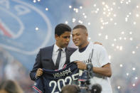 PSG President Nasser Al-Khelaifi, left speaks to PSG's Kylian Mbappe who holds a shirt with his name and 2025 on it as it is announced he has signed a three year extension to his contract on the pitch ahead of the French League One soccer match between Paris Saint Germain and Metz at the Parc des Princes stadium in Paris, France, Saturday, May 21, 2022. (AP Photo/Michel Spingler)