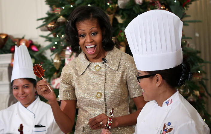 U.S. first lady Michelle Obama reacts as she participates in craft activities with military children at the State Dining Room after a preview of the 2012 White House holiday decorations November 28, 2012 at the White House in Washington, DC. The first lady welcomed military families, including Gold Star and Blue Star parents, spouses and children, to the White House for the first viewing of the 2012 holiday decorations. The theme for the White House Christmas 2012 is "Joy to All." (Photo by Alex Wong/Getty Images)