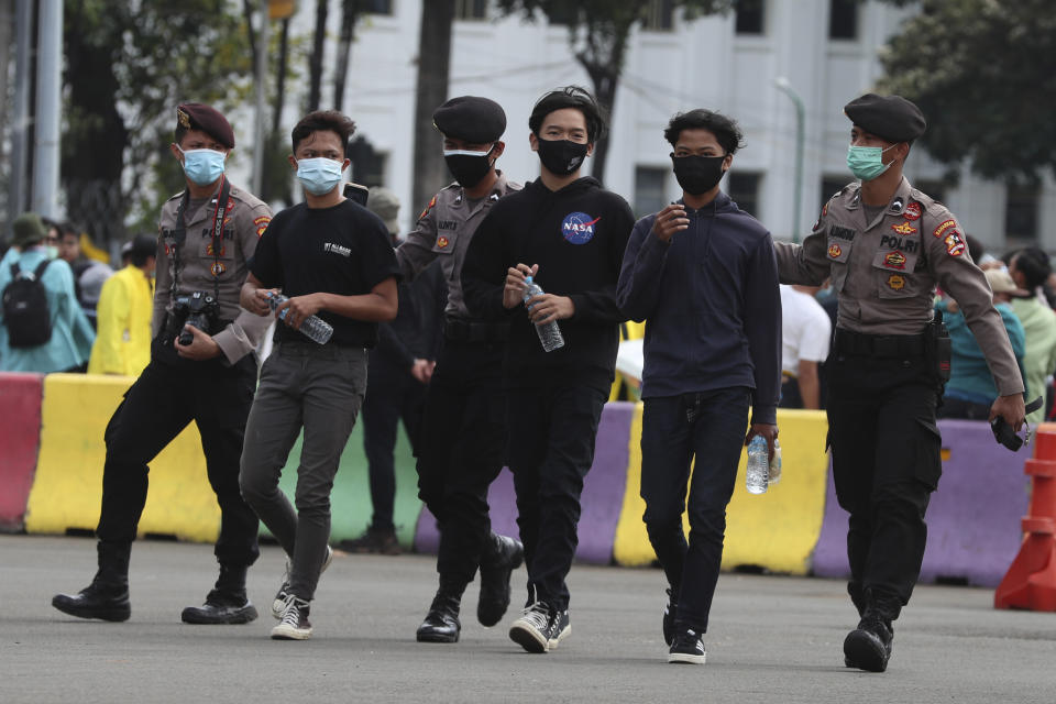 Police officers detain protesters during a rally against the new jobs law in Jakarta, Indonesia, Tuesday, Oct. 20, 2020. Protests against Indonesia's new jobs law were held in cities across the country on Tuesday, with demonstrators calling on the president to revoke the legislation they say will erode labor rights and weaken environmental protections. (AP Photo/Achmad Ibrahim)