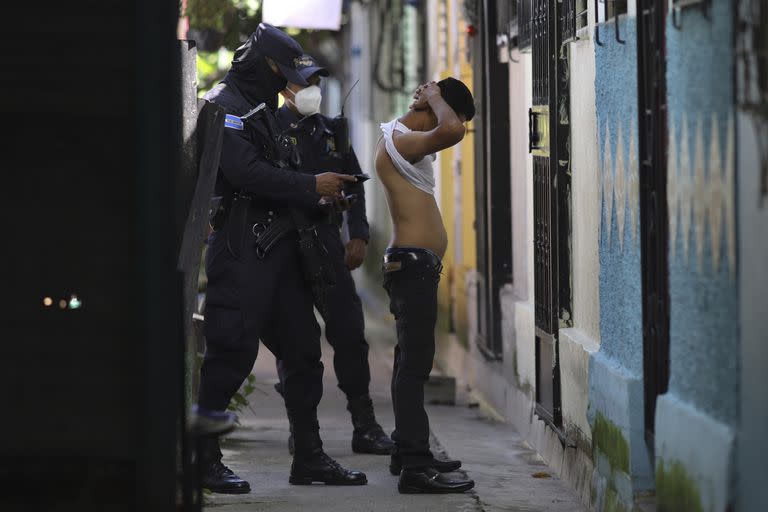 Un policía registra y comprueba la documentación de un hombre que vive en la comunidad Kiwanis, en un patrullaje preventivo en busca de miembros de pandillas en Soyapango, El Salvador, el 16 de agosto de 2022 durante el estado de excepción.