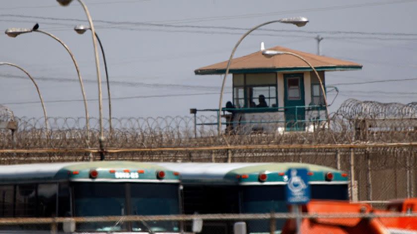 Schaben, Allen J. –– – CHINO: AUG. 10, 2009: As viewed through the afternoon heat waves, a corrections officer looks out from a tower over barbed wire fences and transport busses at the California Institution For Men State Prison in Chino. California prisons remain on lockdown after Saturday's riot in Chino. On Aug. 8 a violent riot broke out at the California Institution of Men in the West reception facility. About 200 inmates were injured and 30 remain hospitalized with non–life threatening injuries. Some say the riot is a result of race–related tensions between Blacks and Latinos.(Allen J. Schaben / Los Angeles Times