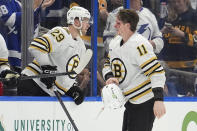 Boston Bruins center Trent Frederic (11) leaves the ice bloodied after a fight with Tampa Bay Lightning left wing Tanner Jeannot (84) during the first period of an NHL hockey game Wednesday, March 27, 2024, in Tampa, Fla. Looking on is Bruins' Parker Wotherspoon (29). (AP Photo/Chris O'Meara)