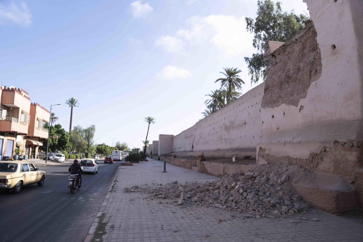 People drive past a damaged wall of the historic Medina of Marrakech, after after an earthquake in Morocco, Saturday, Sept. 9, 2023. A rare, powerful earthquake struck Morocco late Friday night, killing more than 600 people and damaging buildings from villages in the Atlas Mountains to the historic city of Marrakech. (AP Photo/Mosa'ab Elshamy)