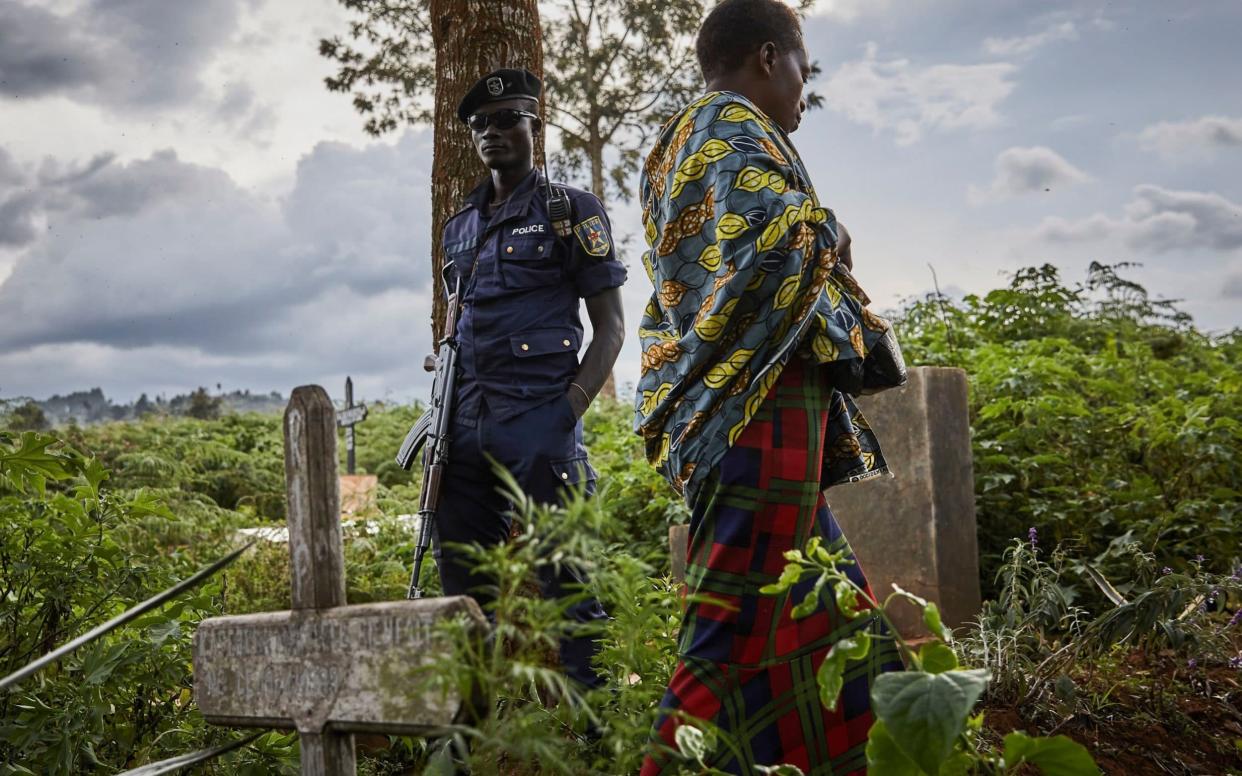 A police officer guards the funeral of Ebola victims in Butembo - REX