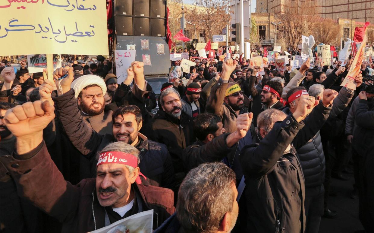 Iranian demonstrators hold placards and chant anti-Britain slogans in front of the British embassy in the capital Tehran on January 12 - AFP