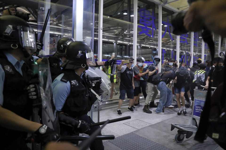 Policemen in riot gears use pepper spray on the protesters during a demonstration at the Airport in Hong Kong, Tuesday, Aug. 13, 2019. Chaos has broken out at Hong Kong's airport as riot police moved into the terminal to confront protesters who shut down operations at the busy transport hub for two straight days. (AP Photo/Kin Cheung)