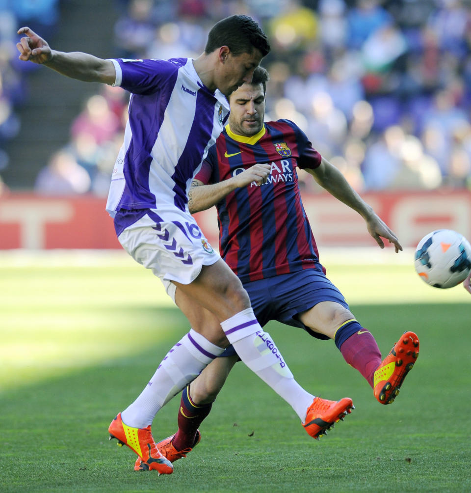 Barcelona's Cesc Fabregas, right, challenges Valladolid's Jesus Rueda for the ball during a Spanish La Liga soccer match at the Jose Zorrilla stadium in Valladolid, Spain, Saturday March 8, 2014. (AP Photo/Israel L. Murillo)