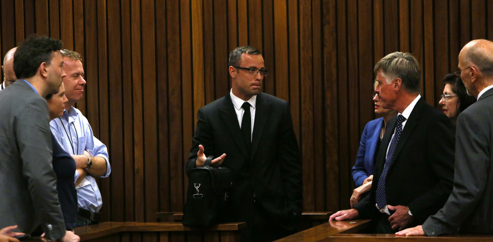 Oscar Pistorius, center, speaks with family and friends, right, as press, left, look on, as the prosecution wrapped up it's case in Pretoria, South Africa, Tuesday, March 25, 2014. Pistorius is charged with the Valentines Day 2013 shooting death of his girlfriend Reeva Steenkamp. (AP Photo/Esa Alexander, Pool)