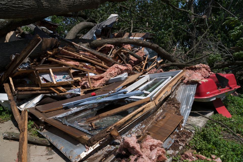 Debris from a trailer home is scattered under a fallen tree in the Village of Keensburg, Ill., Friday, May 20, 2022. Heavy storm winds came through the area Thursday night causing significant damage. 