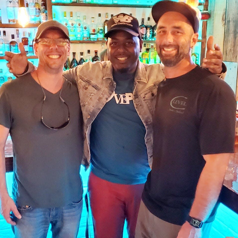 Kreskin J. Torres, "The Rideshare Foodie," center, stands with owners Chaz Nay and Rich Blackford of C-Level Bar and Grill on his visit to Bay County.