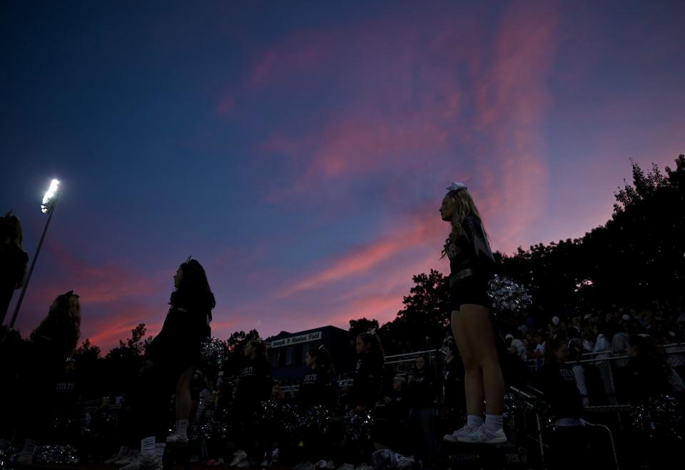 The Medway cheerleaders follow the action as the sun sets during the Mustangs home opener against Westwood at Medway High School, Sept. 29, 2022.  