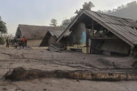 Villagers inspect the damage as houses are seen buried in volcanic ash from the eruption of Mount Semeru in Kajar Kuning village in Lumajang, East Java, Indonesia, Monday, Dec. 5, 2022. Indonesia's highest volcano on its most densely populated island released searing gas clouds and rivers of lava Sunday in its latest eruption. (AP Photo/Imanuel Yoga)