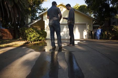 Water conservation official Steven Upton (L) gives a warning to a resident who is watering on a mandatory "no watering" day, in this August 15, 2014 file photo in Sacramento, California. REUTERS/Max Whittaker/Files