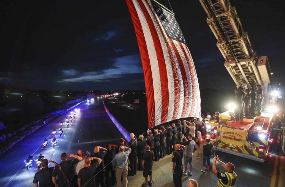 FILE - In this Aug. 15, 2018 file photo, Utah firefighter Matt Burchett, 42, who died fighting a wildfire in California, is honored by a detail along Murray Parkway as his body is returned home, traveling along Interstate 215 after being flown to the Utah Air National Guard in Salt Lake City, Utah. The "blue sheet" summary report by California fire officials says Battalion Chief Matthew Burchett was struck by falling tree debris on Aug. 13 at the Mendocino Complex Fire after a large air tanker completed a drop. (Francisco Kjolseth/The Salt Lake Tribune via AP, File)